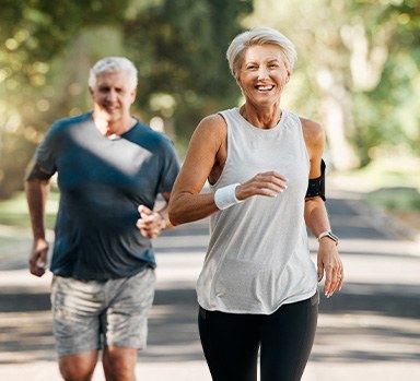 Senior couple smiling while running on trail