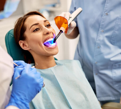 Woman with brown hair in blue bib undergoing dental bonding procedure