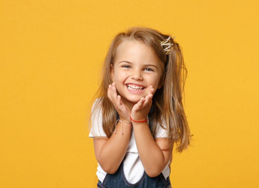 Happy, smiling little girl against yellow background