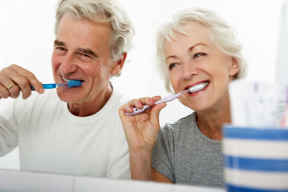 A man and woman brushing their teeth